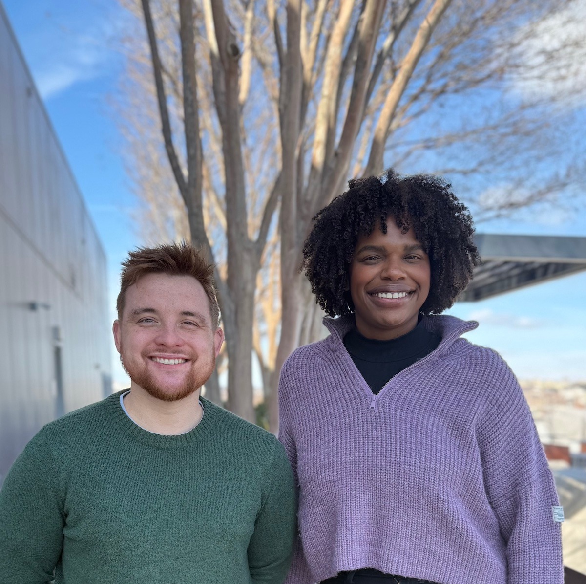 two staff pose outdoors in front of a tree